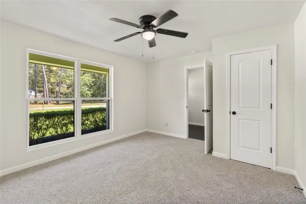 an empty room with ceiling fan and window