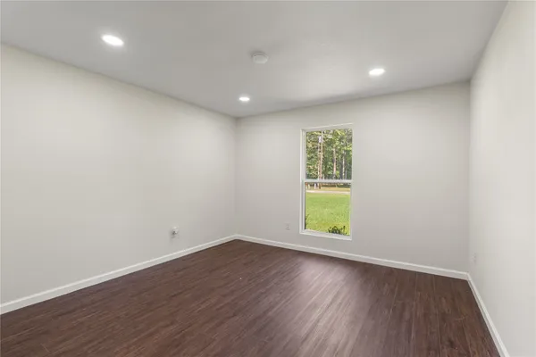 an empty room with wooden floor and window