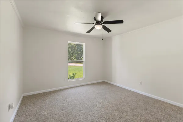 an empty room with a window and a fan