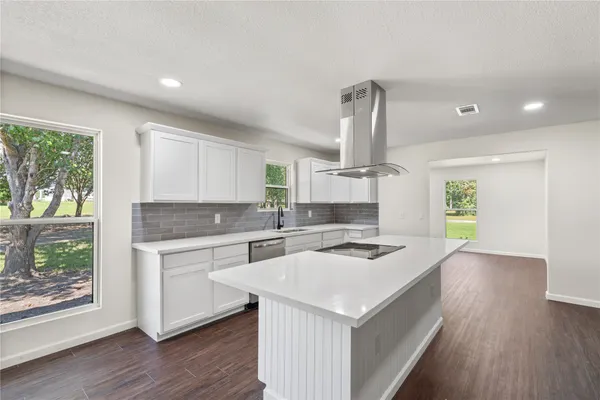 a kitchen that has a sink a microwave oven a stove and white cabinets with wooden floor