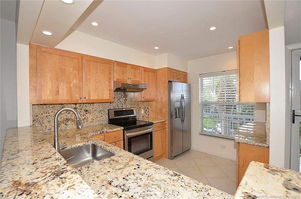 1866 Southwest Palm City Road, Unit 302 Stuart, FL 34994 - Photo 11 of 30 a kitchen with granite countertop a refrigerator and a sink
