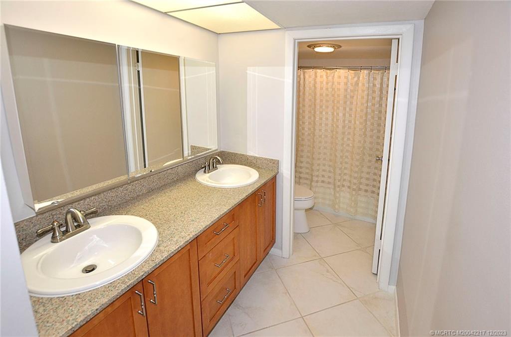 1866 Southwest Palm City Road, Unit 302 Stuart, FL 34994 - Photo 23 of 30 a bathroom with a double vanity sink and a mirror