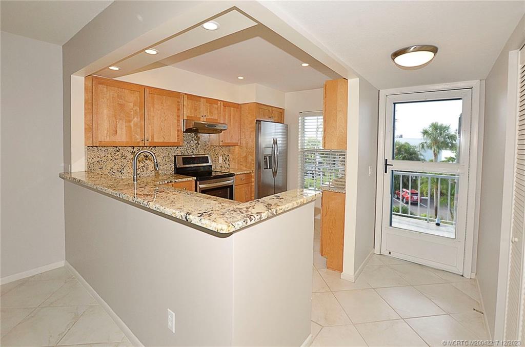 1866 Southwest Palm City Road, Unit 302 Stuart, FL 34994 - Photo 10 of 30 a kitchen with stainless steel appliances granite countertop a refrigerator a sink a stove and white cabinets with wooden floor