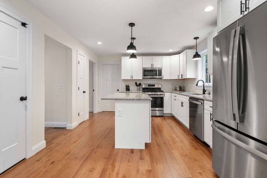 813 Chase Road Lunenburg, MA 01462 - Photo 5 of 41 a kitchen with stainless steel appliances granite countertop a refrigerator a sink dishwasher a stove and white countertops with wooden floor