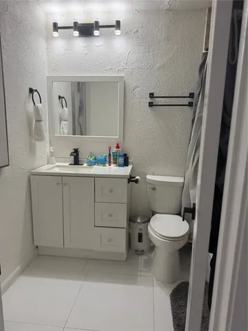 a bathroom with a toilet sink vanity granite and mirror