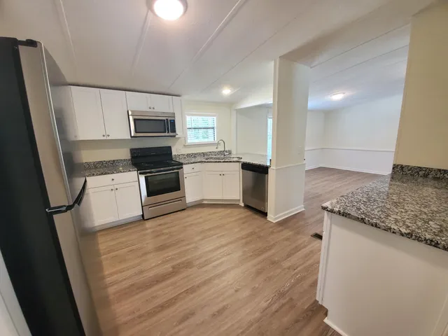 a kitchen with granite countertop a refrigerator stove and sink