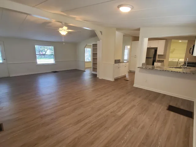 an empty room with wooden floor and windows