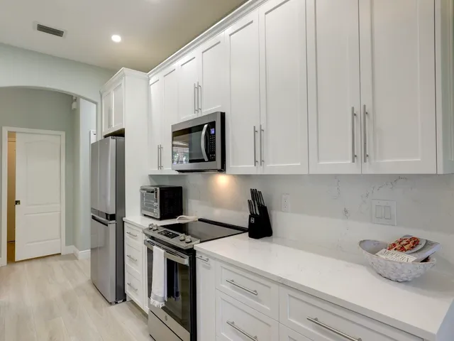 a kitchen with stainless steel appliances granite countertop a kitchen island a stove a table and chairs