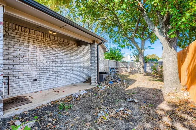 a view of backyard with wooden fence and large trees