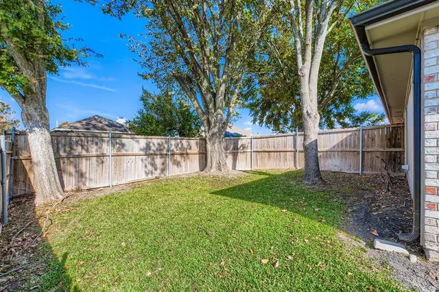 a view of backyard with large trees and wooden fence