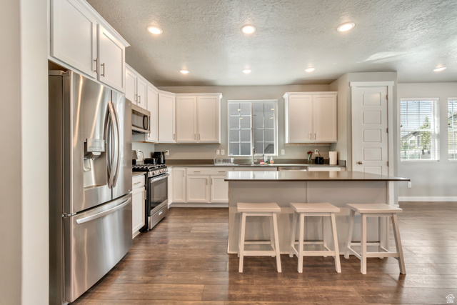 3232 West 1670th Street North Provo, UT 84601 - Photo 12 of 33 Kitchen featuring stainless steel appliances, white cabinetry, a breakfast bar, dark wood finished floors, and recessed lighting