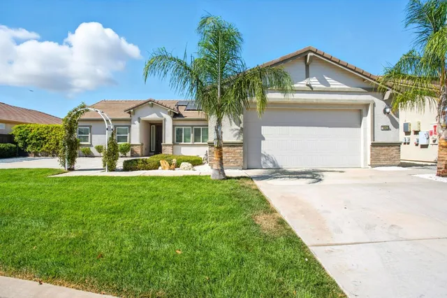 a front view of a house with a yard and palm trees