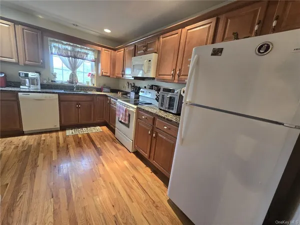 a kitchen with wooden floors and white stainless steel appliances