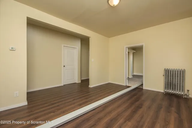 an empty room with wooden floor and a fireplace