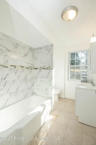 a view of an empty room with wooden floor and a fireplace