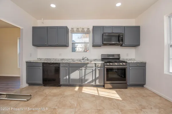 a kitchen with granite countertop a stove top oven and cabinets