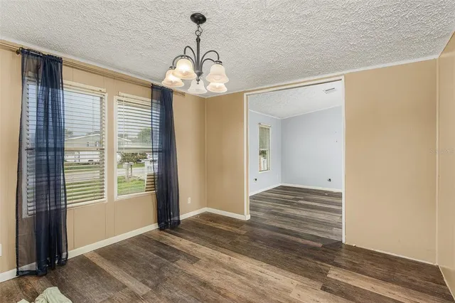 a view of a hallway with wooden floor and chandelier
