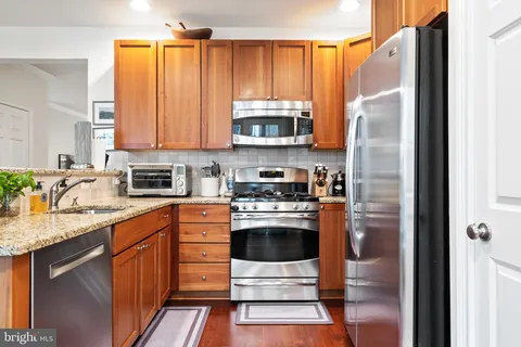 a kitchen with stainless steel appliances granite countertop a refrigerator a stove a sink and a microwave