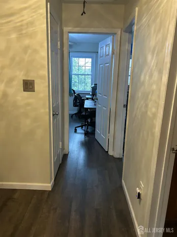 a view of a hallway with wooden floor and a bathroom