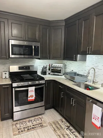 a kitchen with stainless steel appliances granite countertop a stove a sink and a microwave