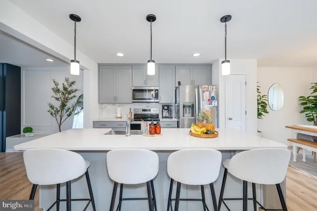 a kitchen with stainless steel appliances kitchen island granite countertop a dining table chairs and a white cabinets