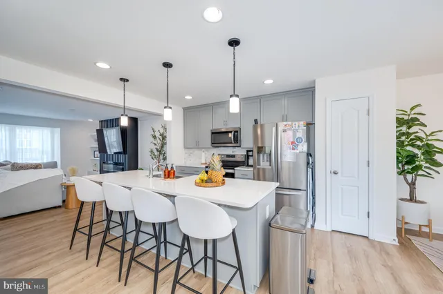 a kitchen with stainless steel appliances a dining table chairs refrigerator and microwave