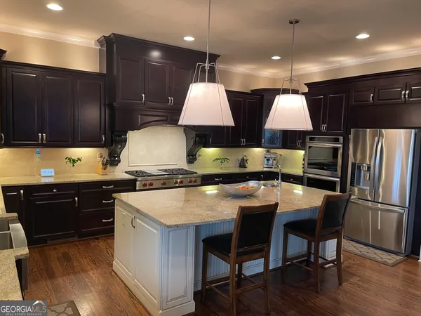 a kitchen with stainless steel appliances a stove a sink a oven a dining table and chairs