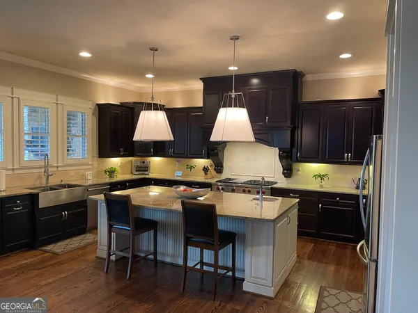 a kitchen with granite countertop a stove a sink a refrigerator and wooden cabinets