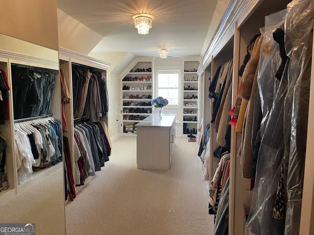 a view of walk in closet with clothes and shoes