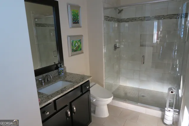 a bathroom with a granite countertop sink a toilet and shower