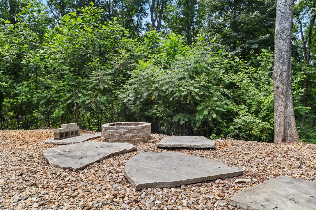 332 Two Rivers Drive Westminster, SC 29693 - Photo 12 of 50 An inviting stone fire pit area, nestled amidst lush natural landscaping, perfect for gatherings.