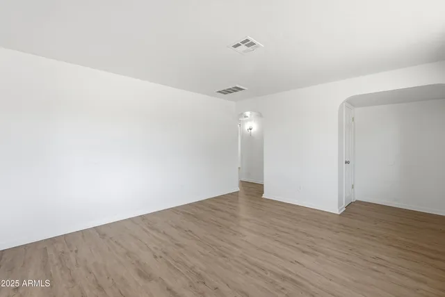 an empty room with wooden floor and ceiling fan