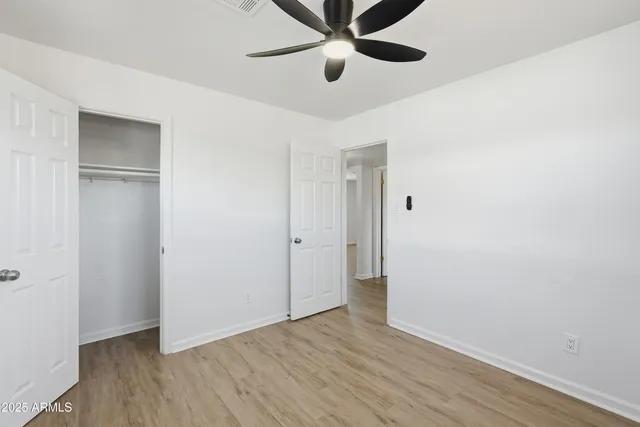 an empty room with wooden floor and ceiling fan