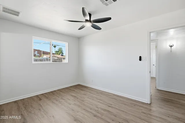 an empty room with a window and a ceiling fan