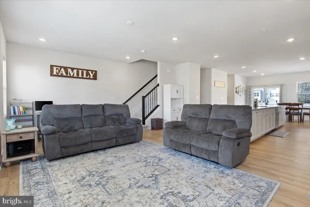 a living room with couches and kitchen view with wooden floor