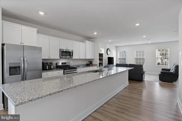 a large kitchen with granite countertop a large counter top stainless steel appliances and cabinets