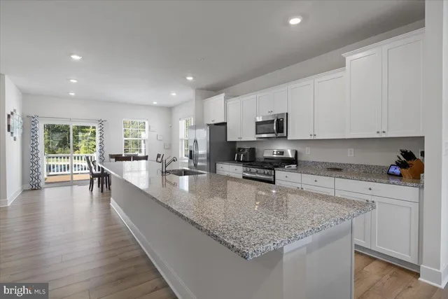 a kitchen with stainless steel appliances granite countertop a sink dishwasher stove top oven and cabinets with wooden floor