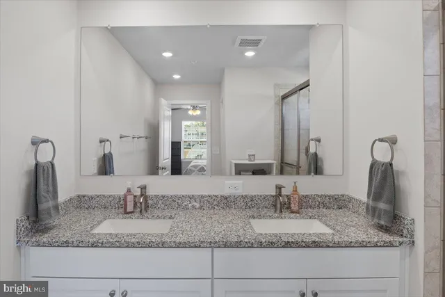 a bathroom with double vanity sinks granite and a mirror