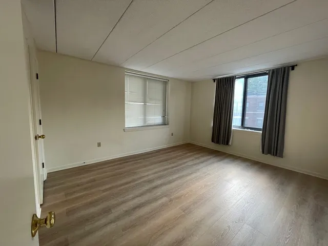 an empty room with wooden floor and windows