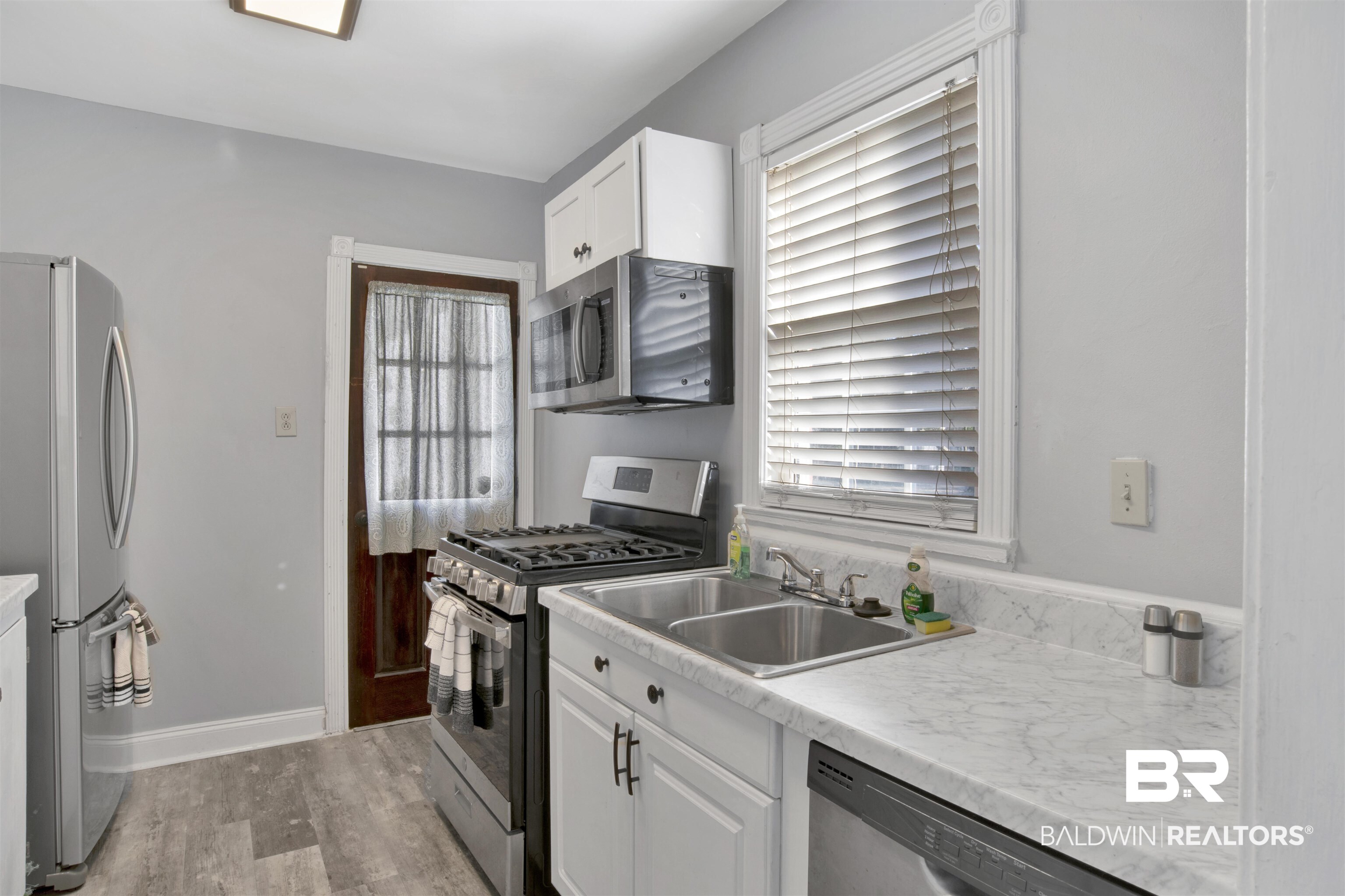 214 Upham Street, Unit 7A Mobile, AL 36607 - Photo 4 of 35 Kitchen featuring stainless steel appliances, white cabinets, light countertops, and light wood-type flooring