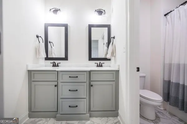 a bathroom with a double vanity sink a toilet and a mirror