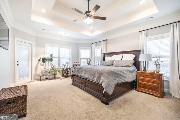 a spacious bedroom with a bed ceiling fan and a window