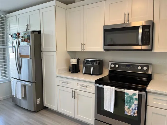 a kitchen with stainless steel appliances white cabinets and a stove a refrigerator with wooden floor