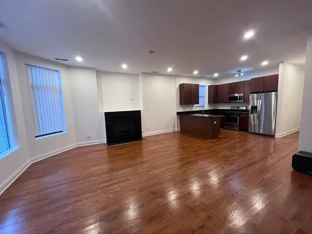 a view of kitchen with kitchen island wooden floor appliances and living room