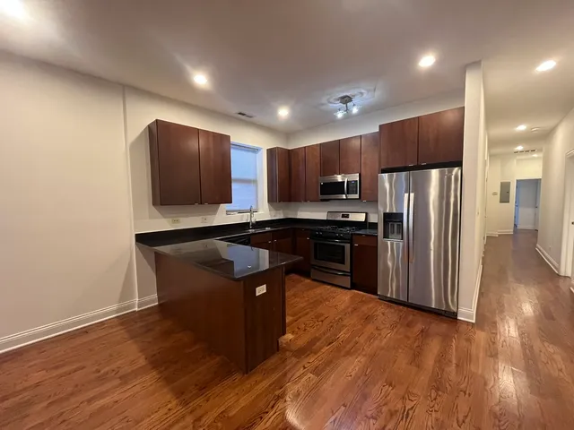 a kitchen with stainless steel appliances kitchen island granite countertop a refrigerator and a stove top oven