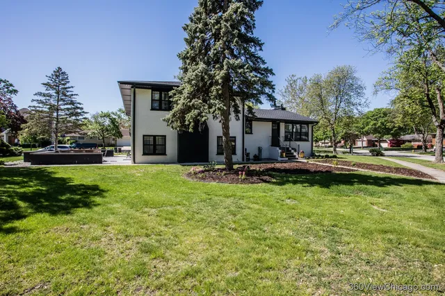 a front view of a house with garden and trees