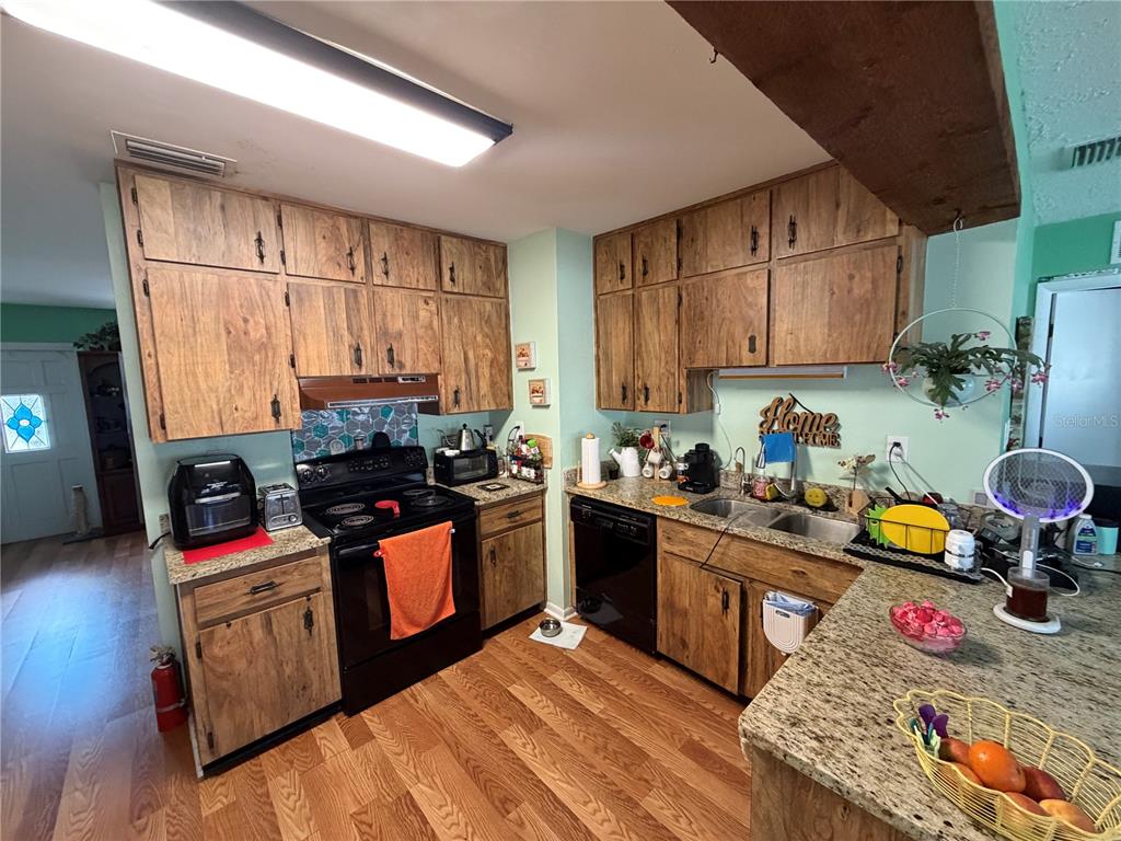 7016 Filbert Lane Temple Terrace, FL 33637 - Photo 10 of 31 a kitchen with stainless steel appliances granite countertop a stove a sink dishwasher and cabinets with wooden floor
