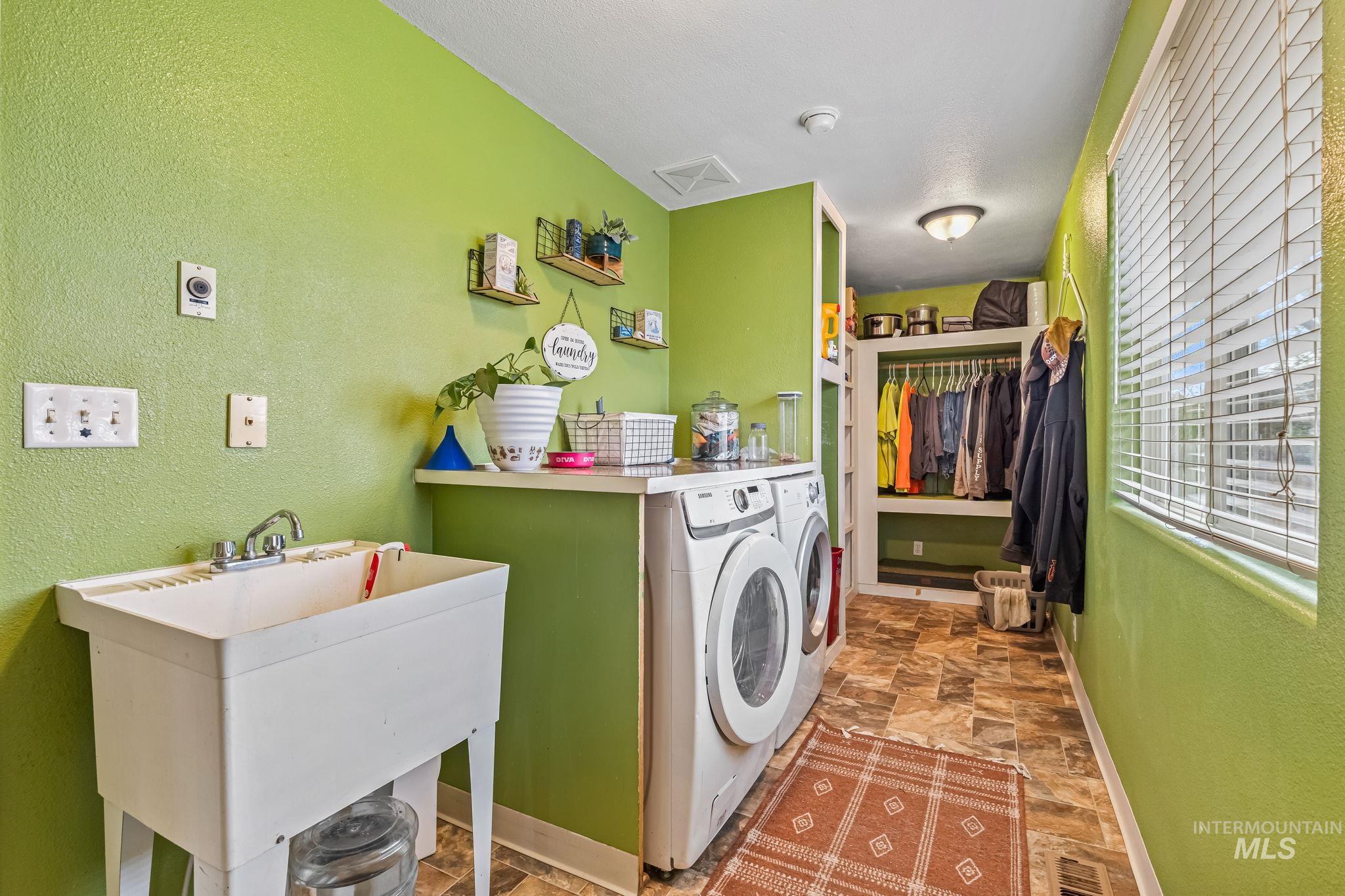 7650 West Colt Drive Boise, ID 83709 - Photo 13 of 30 Laundry area featuring a textured wall, stone finish flooring, and washing machine and dryer