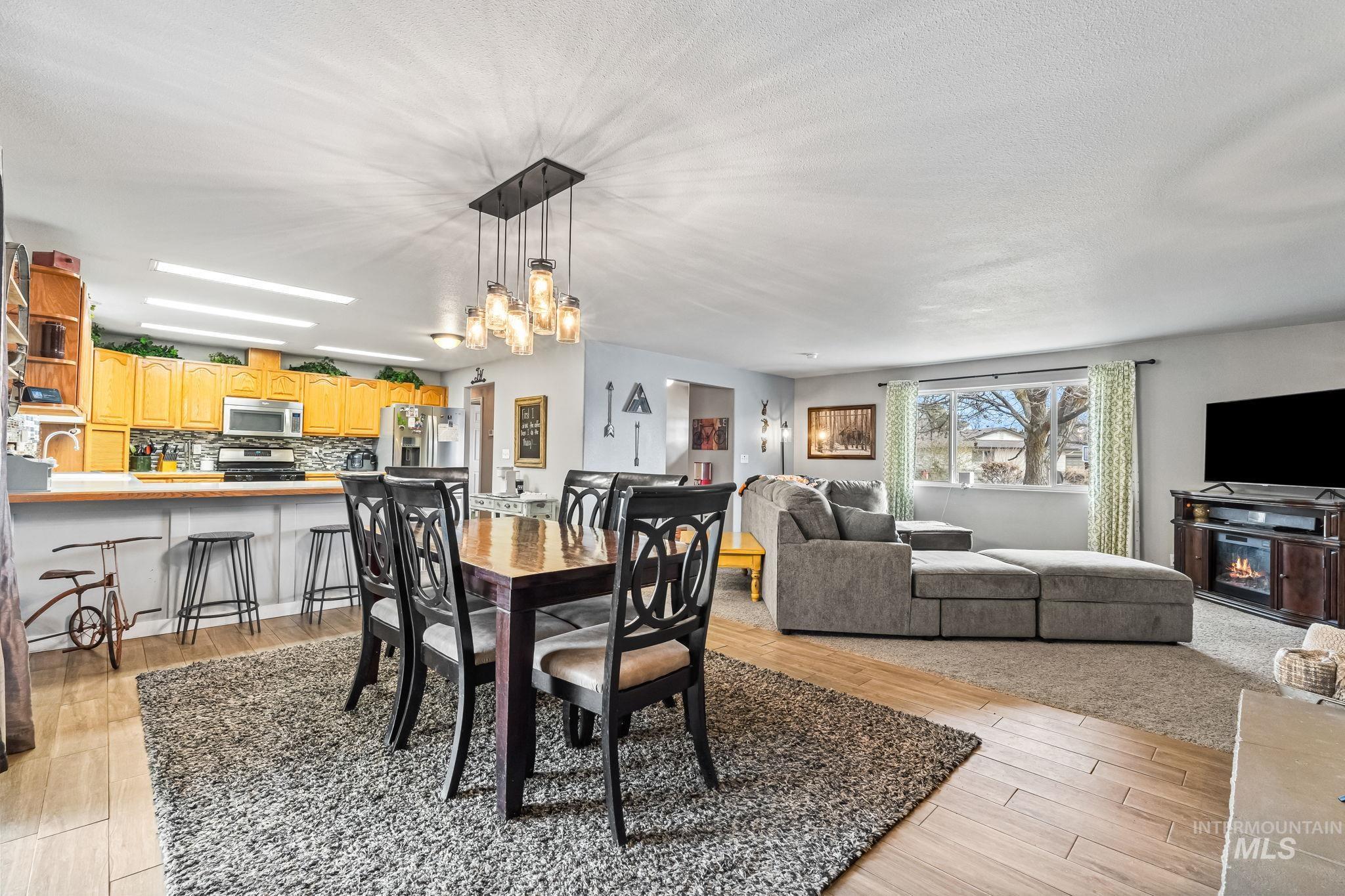7650 West Colt Drive Boise, ID 83709 - Photo 10 of 30 Dining room featuring light wood-style flooring and a glass covered fireplace
