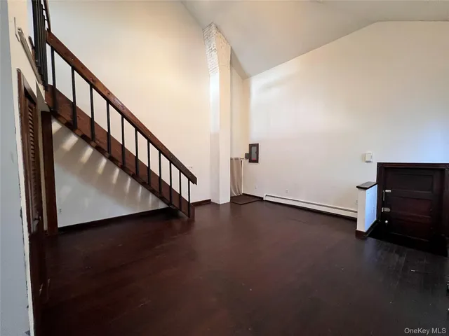 a view of an empty room with wooden floor and stairs